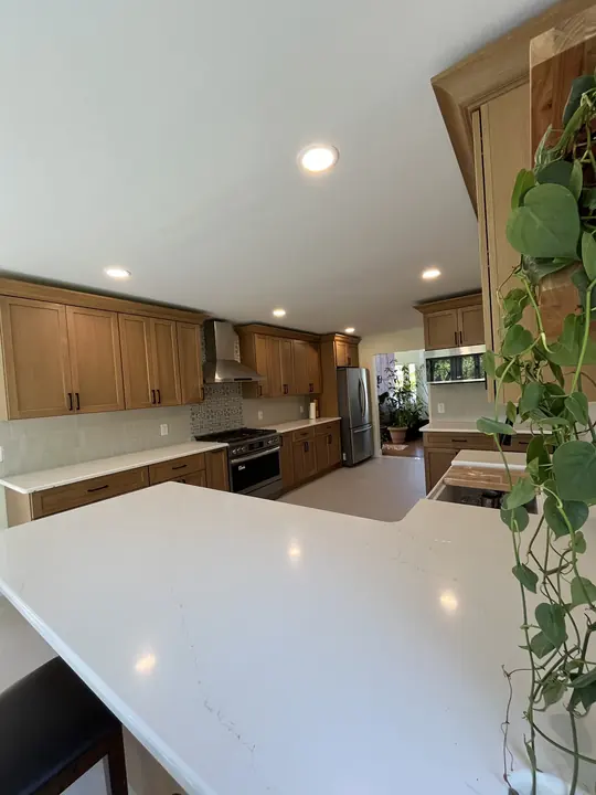 Oak shaker kitchen with white quartz peninsula and stainless range hood