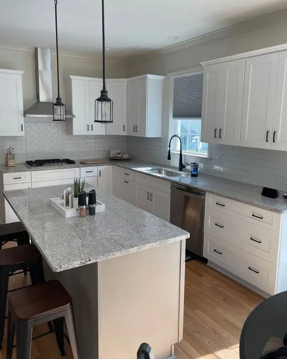 White kitchen with granite island and herringbone accent tile